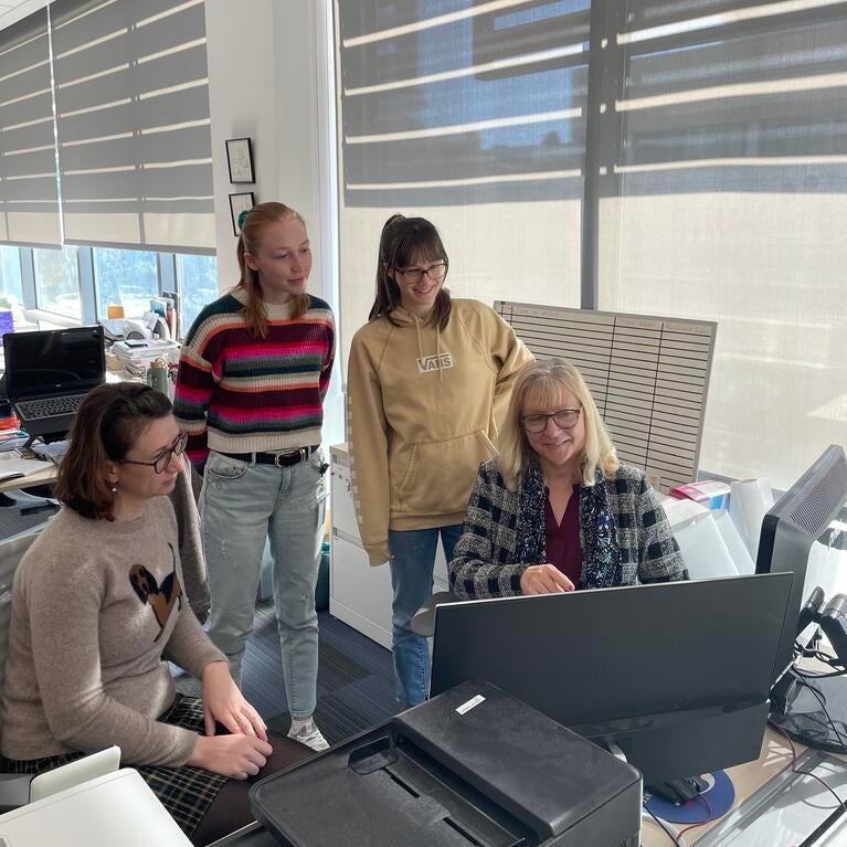 Dr. Iryna Ethell sitting at a computer surrounded by students