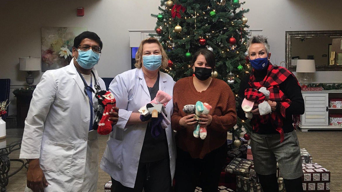 people with socks standing in front of Christmas tree