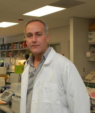 Marcus Kaul, PhD standing in a white coat