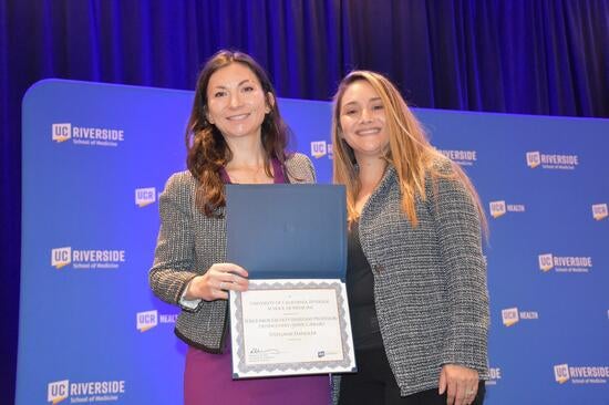 Stephanie Handler, MD,, with one of her three awards. Presenter Margie Burnett is at right.